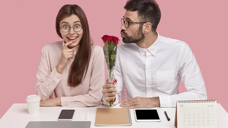 Hombre sorprendiendo a su pareja con rosas en la oficina durante San Valentín.